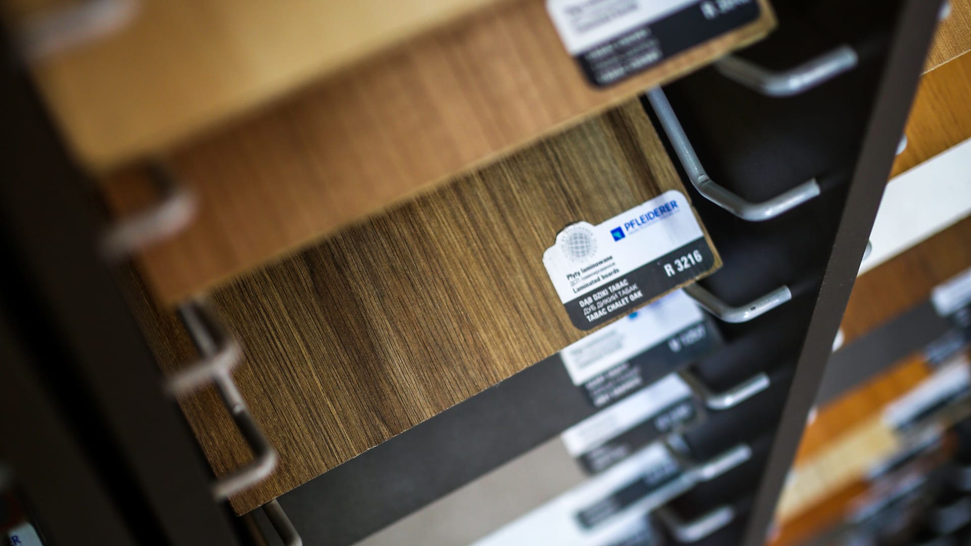 Próbki płyt laminowanych na stojaku z etykietami producenta i kodami dekorów